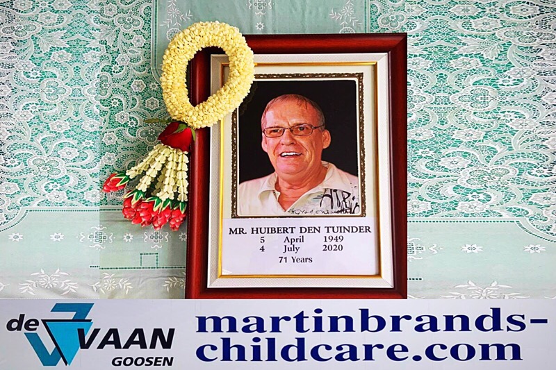 Huib kijkt met een lachend gezicht over de schouder van een engeltje naar de kinderen van de Vaan & Goosen stichting in Pattaya