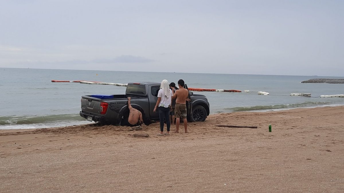 Thaise man maakt een illegaal strandritje op Pattaya Beach en komt met zijn pick-up truck vast in het zand te zitten