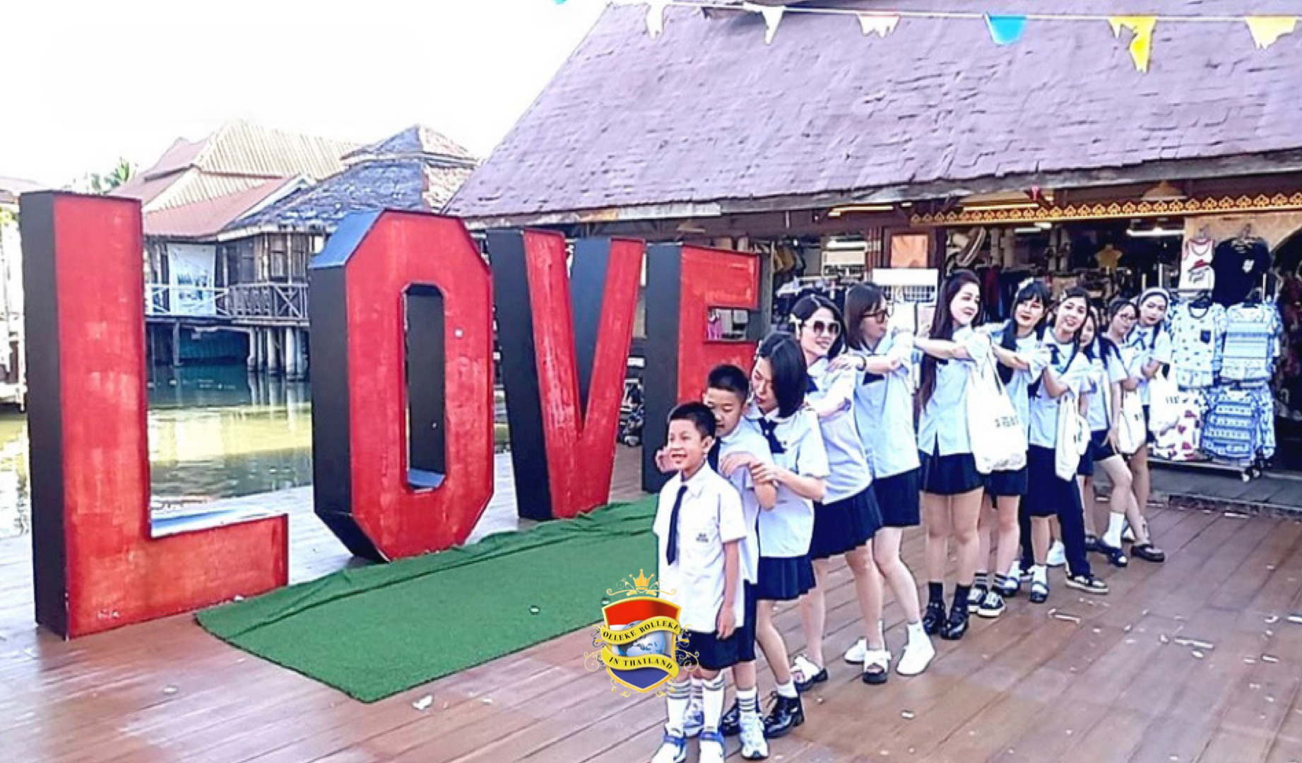 Bezoekers kijken verbaasd naar 300 Chinese toeristen die in Thaise schooluniformen over de drijvende markt van pattaya lanterfanten