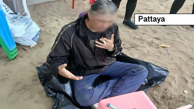 Gemeentelijk personeel en strandwachten verwijderen een Thaise man van het strand om hem in het ziekenhuis mentaal te laten onderzoeken.