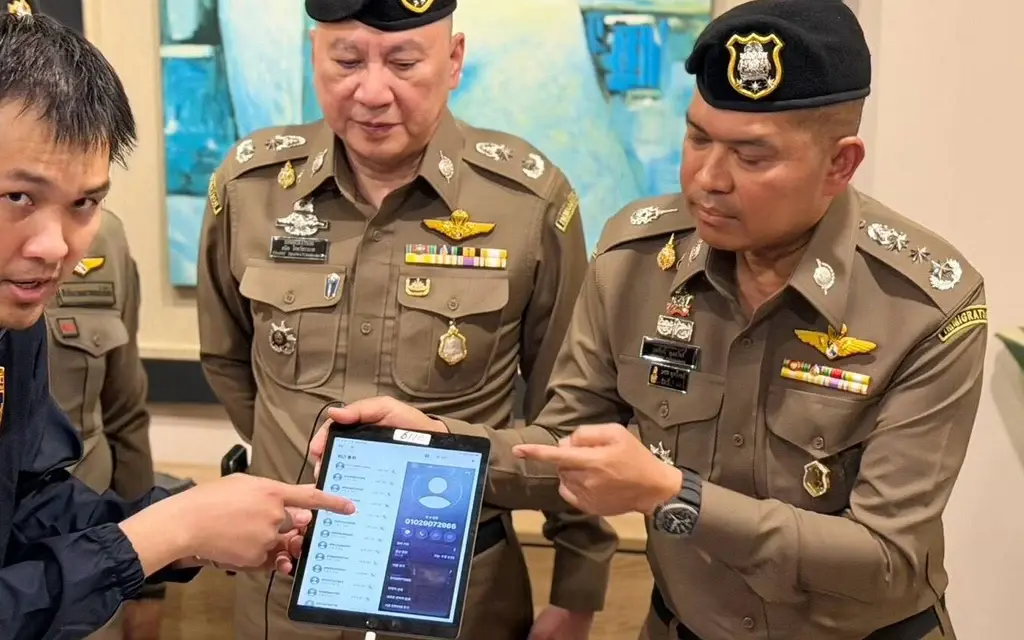 Police officers examine a tablet during an immigration police briefing.
