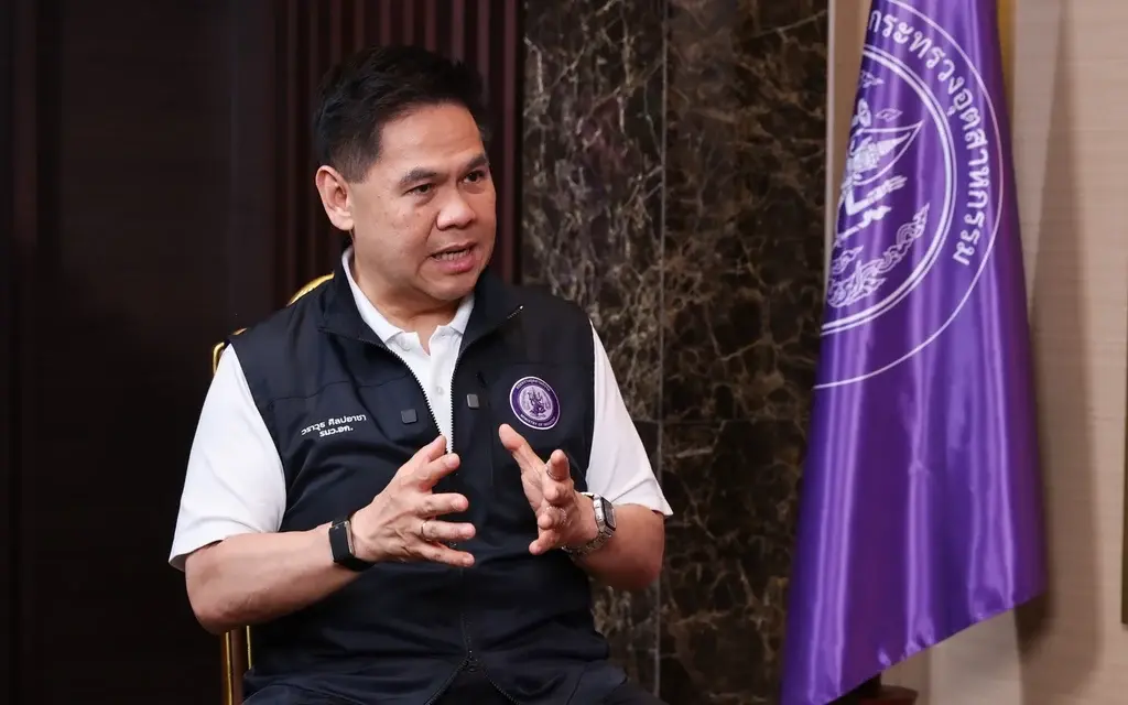Minister speaking beside a purple government agency flag