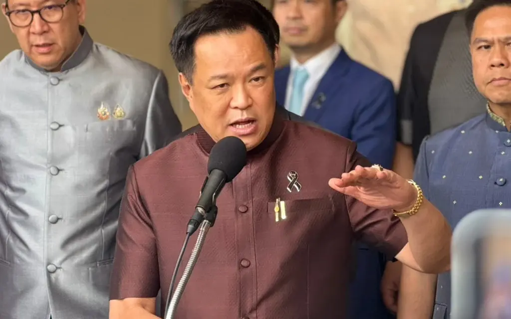 A government official speaks to reporters while colleagues stand behind him.